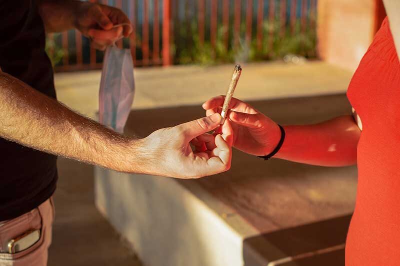 two people passing a joint to one another: closeup of hands